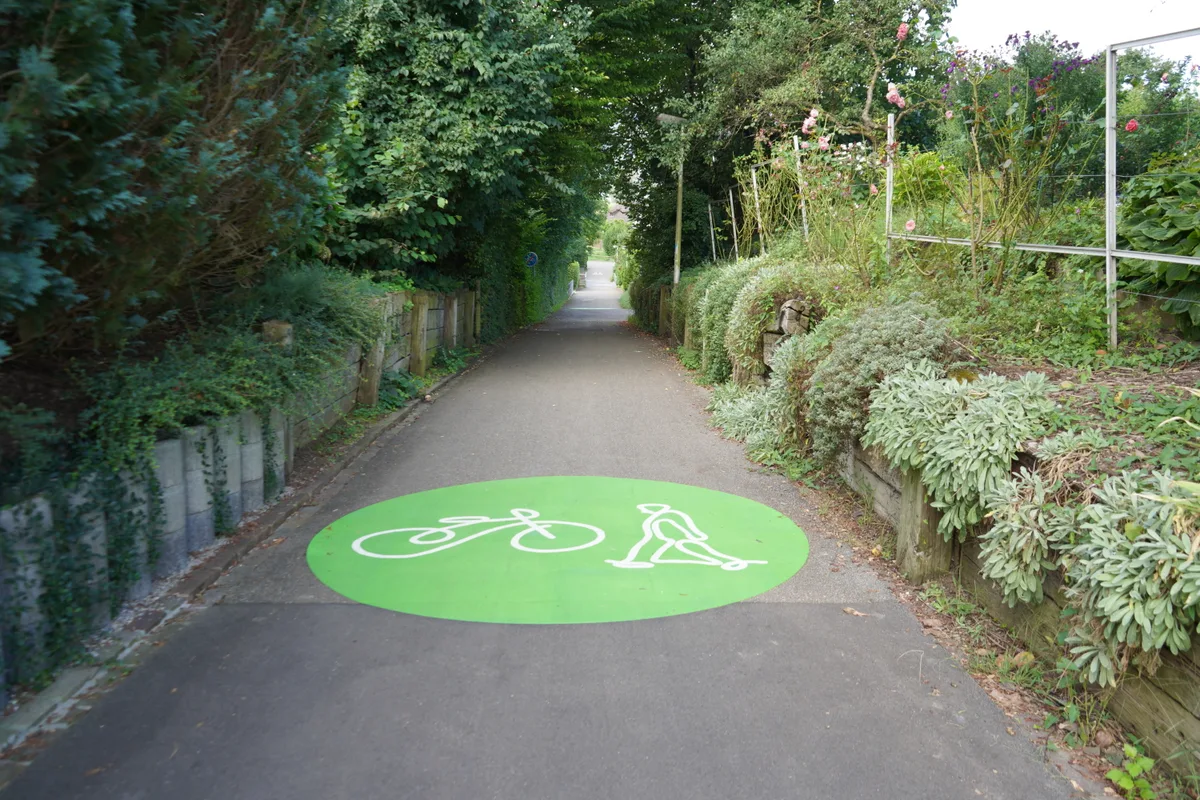 «Uster steigt um!»: grüne Markierung auf dem Boden mit einem Fahrrad und einem Fussgänger.